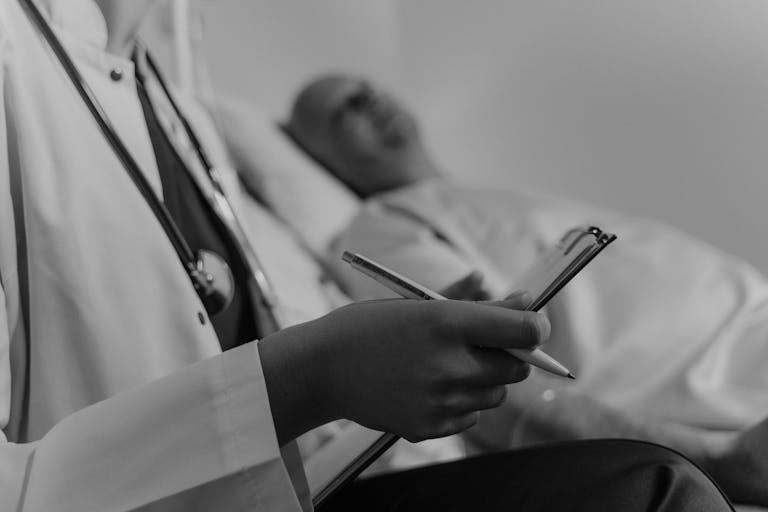 A doctor takes notes while consulting a patient in a hospital setting.